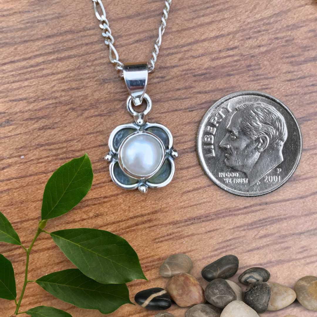 an image of a Dainty Pearl Sterling Silver Floral Pendant next to a dime