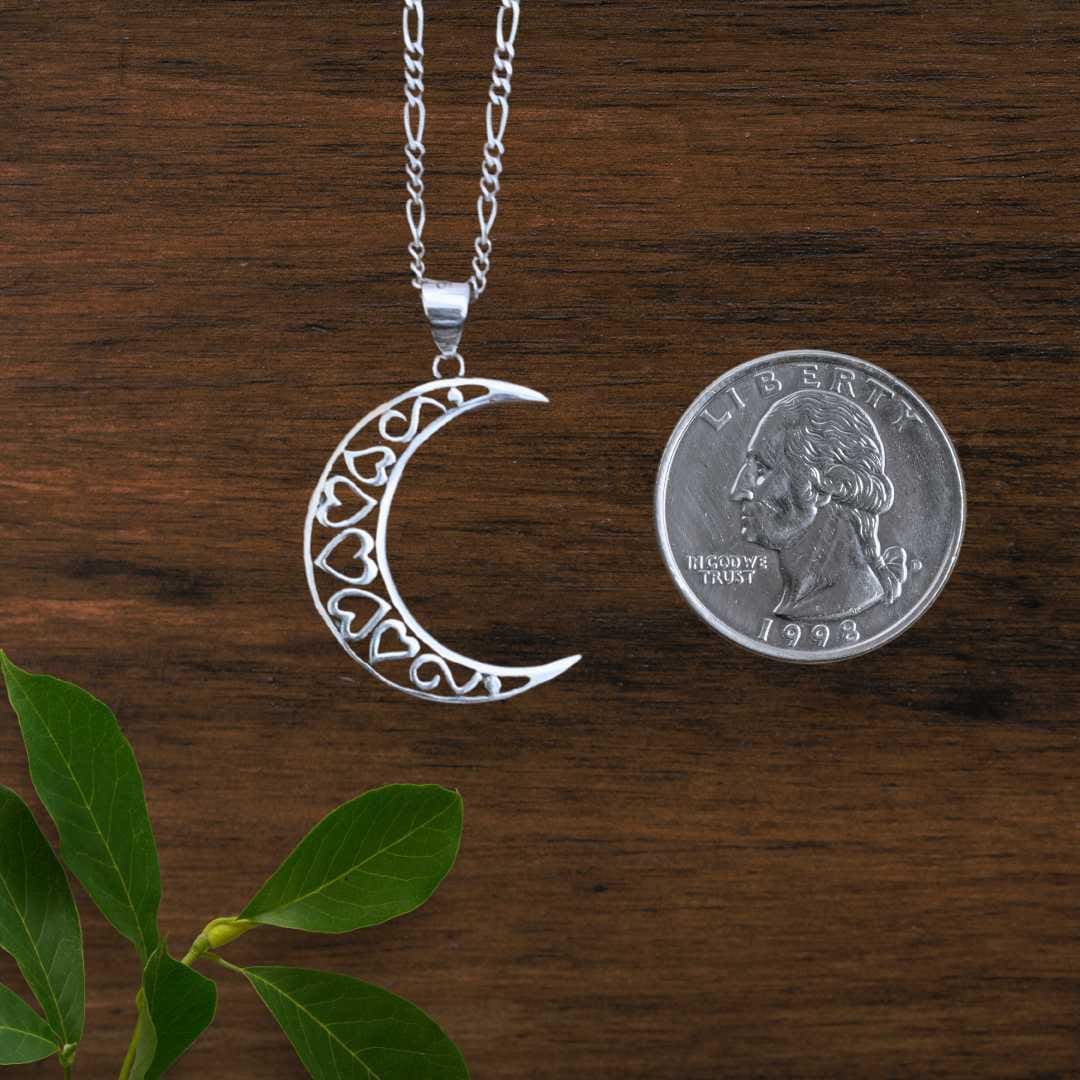 an image of a Sterling Silver Crescent Moon and Open Hearts Pendant next to a quarter