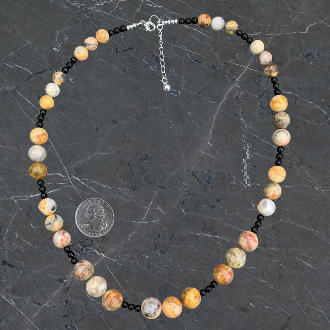 an image of a Crazy Lace Agate and Black Onyx Necklace next to a quarter