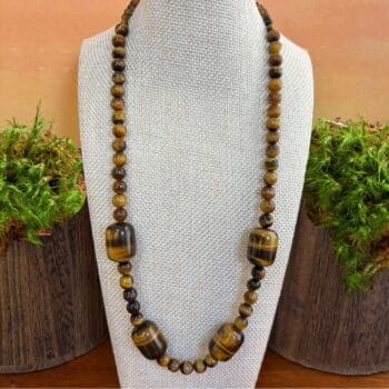 an image of a beaded tiger's eye gemstone necklace featuring four large barrel shaped beads with smaller round beads.