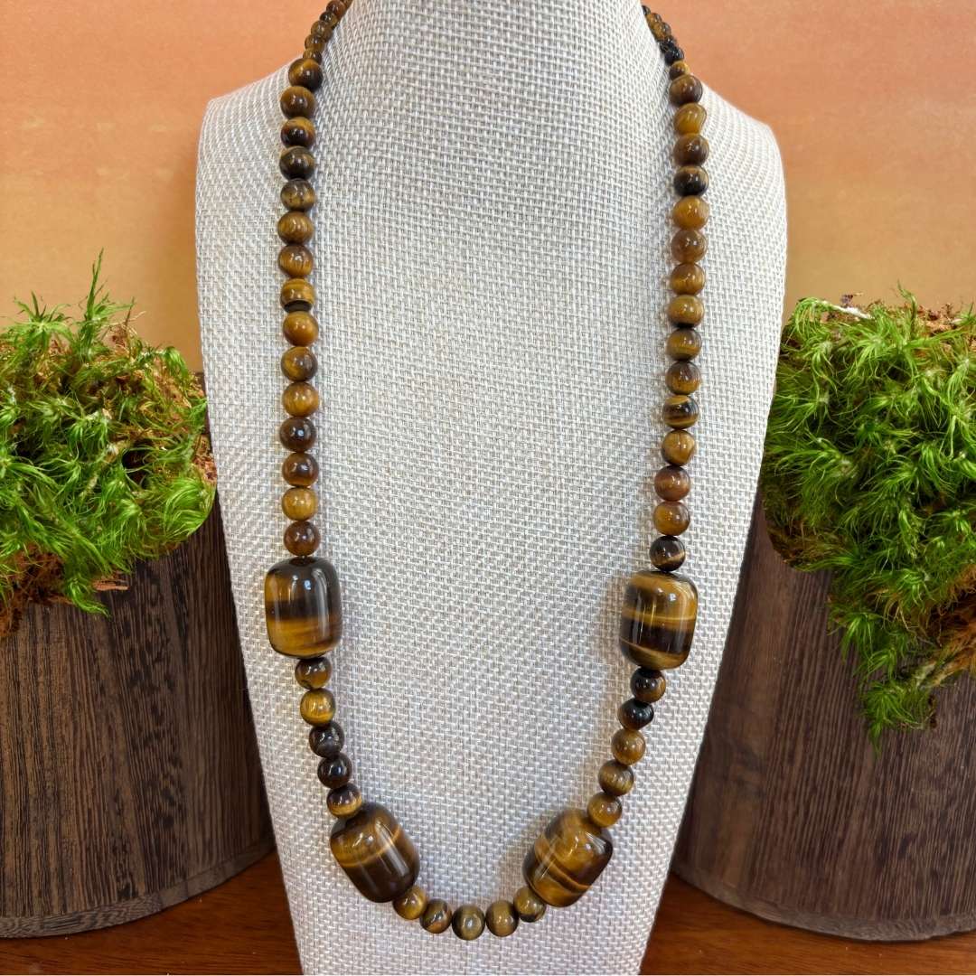 an image of a beaded tiger's eye gemstone necklace featuring four large barrel shaped beads with smaller round beads.