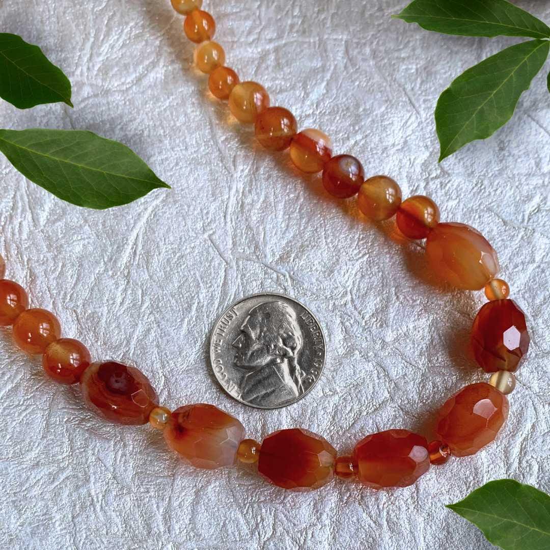 an image of a Faceted Oval Barrels Carnelian Beaded Necklace next to a nickel
