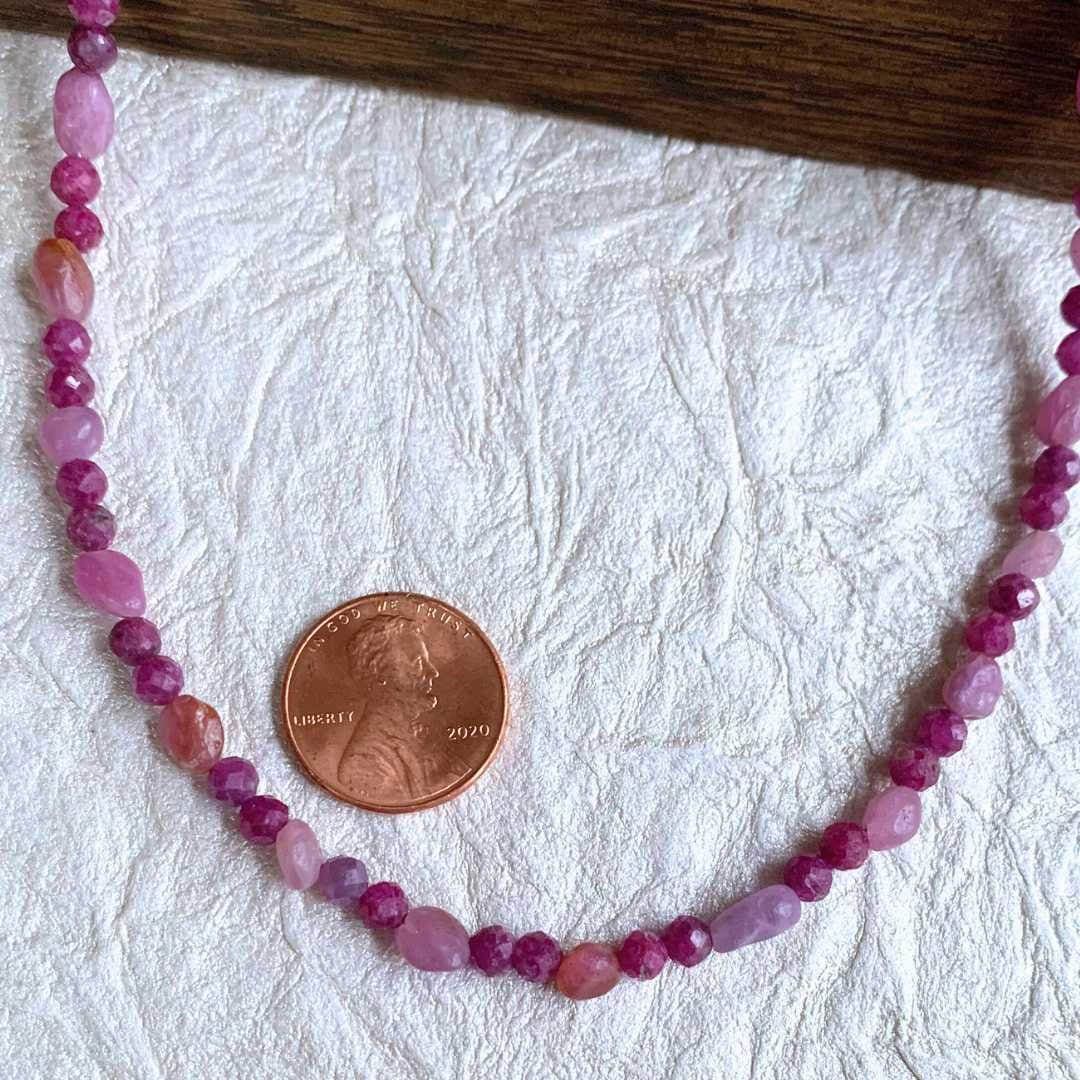 an image of a Dainty Ruby Beaded Necklace next to a penny
