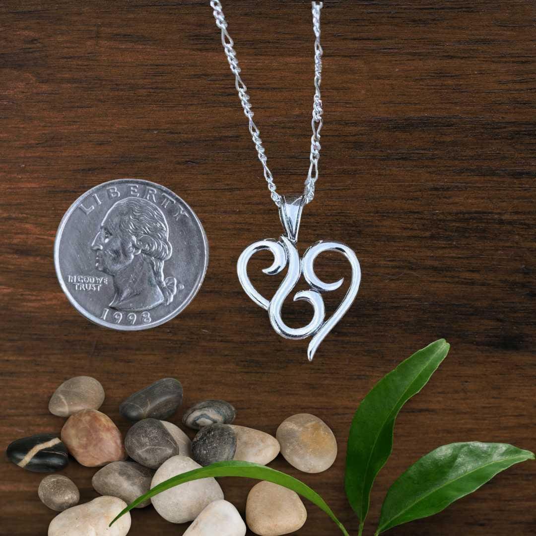an image of a Sterling Swirl Heart Pendant next to a quarter