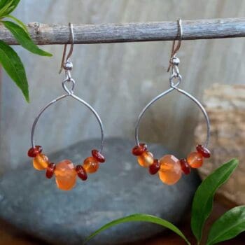an image of a pair of Carnelian and Sterling Silver Dangle Hoop Earrings. There is an open circle with some carnelian beads on it and the hoop hangs from an ear hook