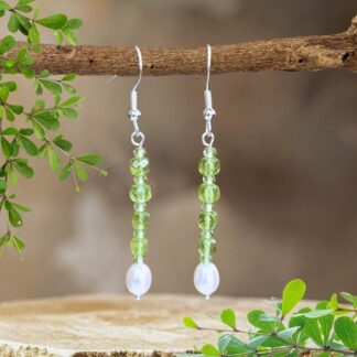 an image of a pair of Stacked Faceted Peridot and Pearl Earrings with 4 faceted peridot cubes spaced with small faceted round peridot beads and anchored by a freshwater pearl. They have a nice amount of dangle and are on a sterling silver earring hook