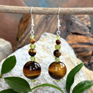 an image of a pair of Tiger's Eye and Peridot Dangle Earrings with three graduated Tiger's Eye round beads separated by small faceted cubes of peridot beads. at the base is a small round peridot heishi bead. They are on sterling silver ear hooks.