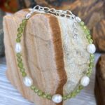 an image of a Faceted Peridot and Pearl Bracelet with 5 freshwater pearls and two sizes of small faceted round peridot beads. It is finished off with sterling silver beads and lobster clasp as well as a sterling silver 1.5 inch extension chain.