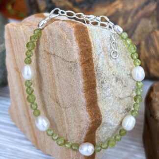 an image of a Faceted Peridot and Pearl Bracelet with 5 freshwater pearls and two sizes of small faceted round peridot beads. It is finished off with sterling silver beads and lobster clasp as well as a sterling silver 1.5 inch extension chain.