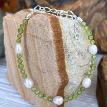 an image of a Faceted Peridot and Pearl Bracelet with 5 freshwater pearls and two sizes of small faceted round peridot beads. It is finished off with sterling silver beads and lobster clasp as well as a sterling silver 1.5 inch extension chain.