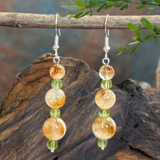 An image of a pair of Citrine and Peridot Beaded Earrings with three graduated round citrine beads separated by three small faceted cube shaped peridot beads. They are on a sterling silver ear hook.