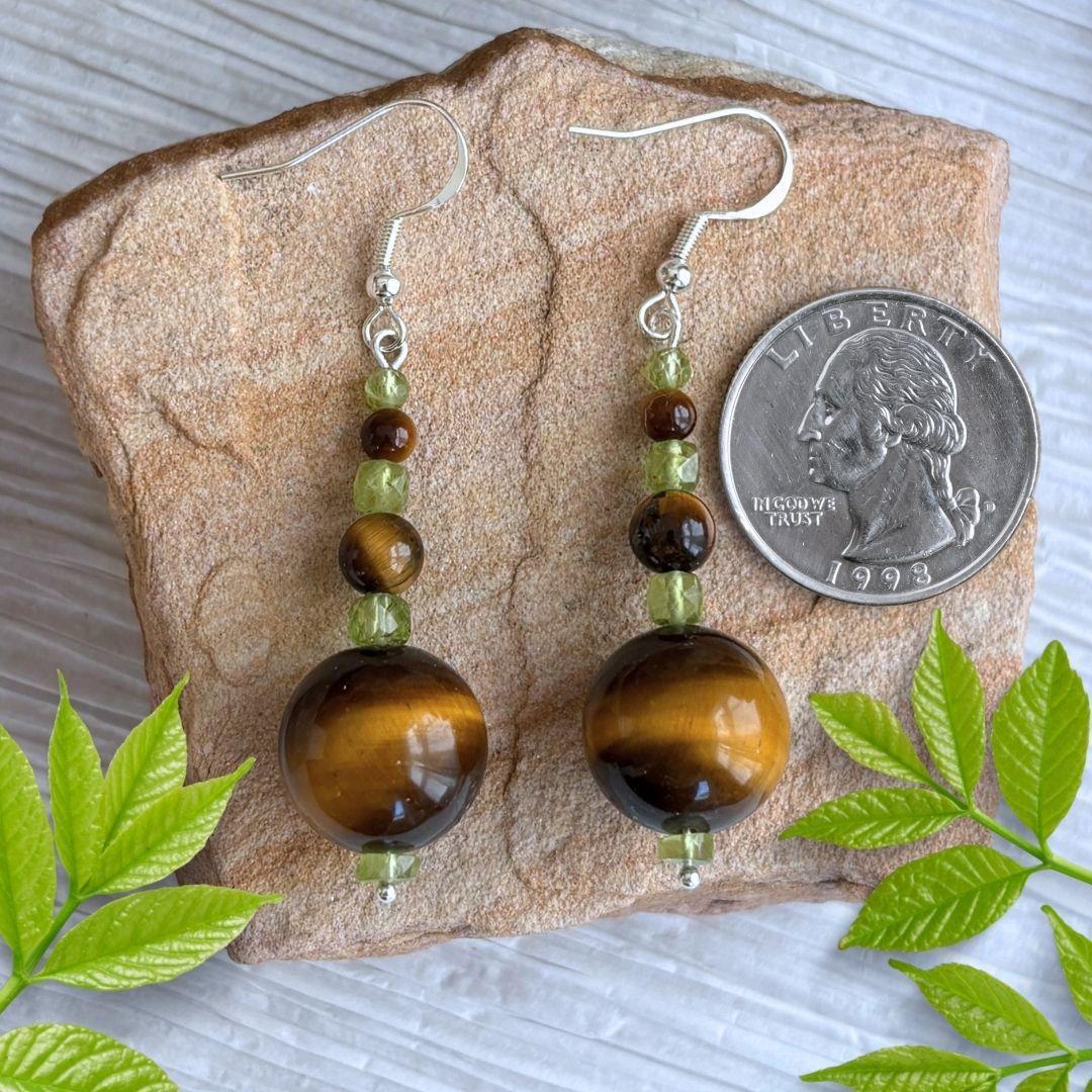 an image of a pair of Tiger's Eye and Peridot Dangle Earrings with three graduated Tiger's Eye round beads separated by small faceted cubes of peridot beads. at the base is a small round peridot heishi bead. They are on sterling silver ear hooks.