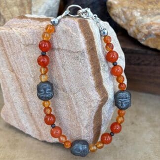 an image of a Gemstone beaded bracelet with 3 hematatite grey buddha head beads and orange and golden carnelian beads