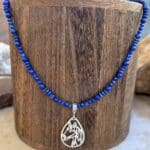 an image of a Lapis Lazuli Beaded Necklace with Horse Pendant featuring two sizes of small round smooth lapis beads with small rondelle beads. The focal point is a silhouette filigree teardrop shaped pendant of a horse's head in sterling silver.